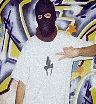 Artiste cagoulé devant un graffiti